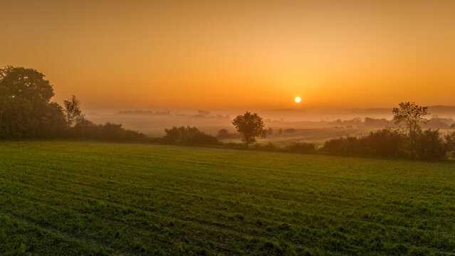 Bocage normand baignant dans une lumi&egrave;re jaune orange rouge sous le soleil levant
