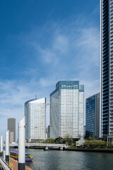 Tokyo city Japan capital cityscape, waterfront skyscrapers and boat at river pier, blue sky