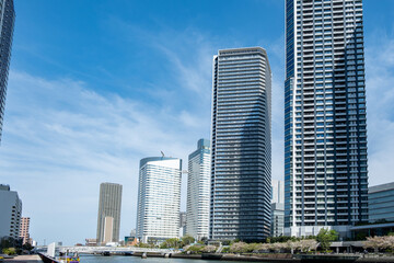 Tokyo city skyline, waterfront skyscrapers against blue sky, Japan capital cityscape