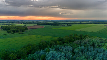 Vue aérienne du coucher de soleil sur fond dramatique très nuageux et orageux au milieu des champs et des forêts du bocage normand en France