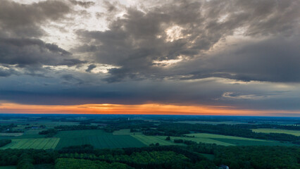 Vue aérienne du coucher de soleil sur fond dramatique très nuageux et orageux au milieu des champs et des forêts du bocage normand en France