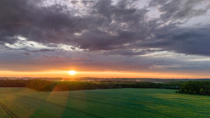 Vue aérienne du coucher de soleil sur fond dramatique très nuageux et orageux au milieu des champs et des forêts du bocage normand en France