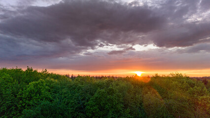 Vue aérienne du coucher de soleil sur fond dramatique très nuageux et orageux au milieu des champs et des forêts du bocage normand en France