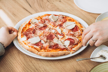 Meat pizza in cafe close-up, father and daughter having lunch in cafe together.