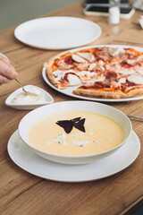 Cheese cream soup and pizza in the home kitchen, homemade food for family lunch.
