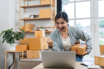 Young Woman Celebrates Successful Online Shopping Business with Excitement and Joy in a Modern Home Office Setting