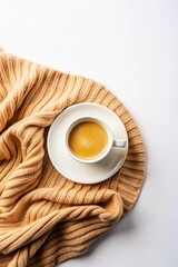White cup of coffee on a saucer on white background with a cozy orange sweater. Copy space. Flat lay