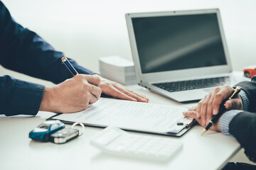 A salesperson is talking to a customer at a showroom with a low interest offer. Special promotion for calculating the cost of renting a new EV car. Buyer agrees to lease an electric vehicle.