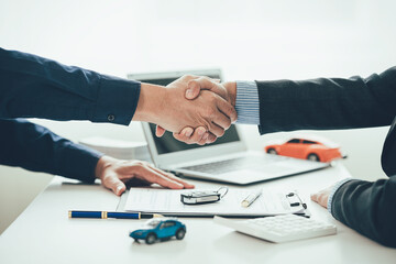 Car dealers shake hands with customers after signing contracts and offer special promotions to customers. And calculate the cost of leasing a new EV car. Close-up photo.