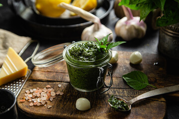Green basil pesto sauce in a glass jar on the table