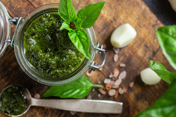 Green basil pesto sauce in a glass jar on the table