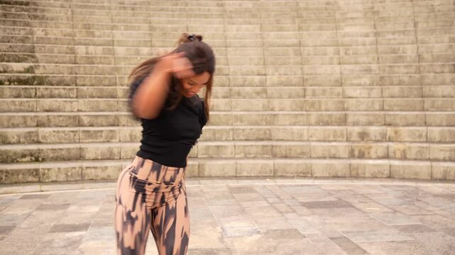 Full length of a latin young woman raising joining arms dancing salsa in a park