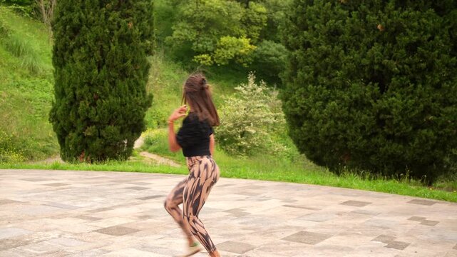 Sensual brunette woman smiling while dancing salsa in a park alone