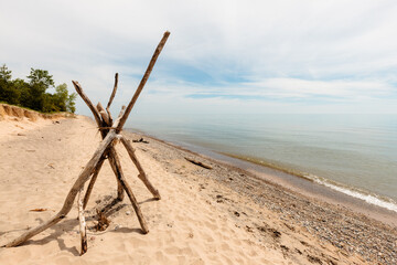 Driftwood is stacked along the beach at Kohler Andrae State Park, Sheboygan, Wisconsin as Lake Michigan is quite calm in mid-June