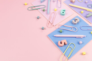 Top view of pink, purple and blue notebooks on pink background. Colorful pens, paperclips, numbers and pins. School, office wallpaper. Flat lay, copy space.