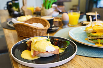 Eggs Benedict with ham on a wooden table