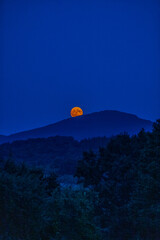The full flower moon -  07, 2024. The rising moon over the mountain peaks , a cloudless night allows observation of the astronomical phenomenon. 