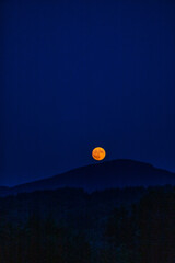 The full flower moon -  07, 2024. The rising moon over the mountain peaks , a cloudless night allows observation of the astronomical phenomenon. 
