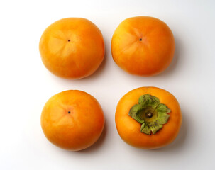 Close-up and top angle view of four ripe persimmons with turned one on white floor, South Korea
