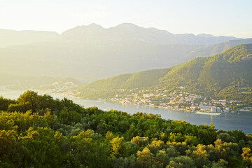 Naklejka premium Summer sunset in the municipality of Herceg Novi: view of the mountains, sea, forest and coastal settlements painted in golden rays of the sun. Evening landscape from the Bay of Kotor, Montenegro.