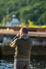 a male landscape photographer at work in Andlasnes Norway Rauma region, photographing the sunrise over the marina