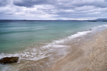 long exposure beach waves around rock cloudy day
