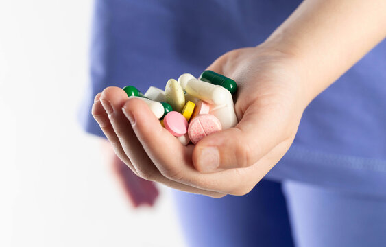 A child holds a handful of multi-colored vitamin tablets in his hand. Concept of vitamins and minerals for a child for immunity and health. B vitamins and omega 3, close-up