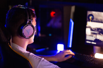 Gamer teenager plays PvP shooter battle royale video game on PC at computer club. Professional...