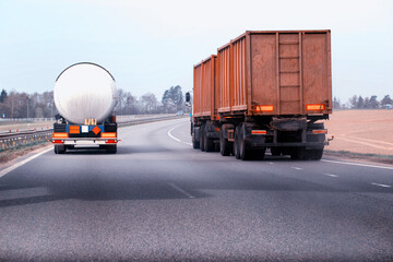 A truck with a semi-trailer tanker transports dangerous cargo along the highway - liquefied gas. Logistics of dangerous goods. Copy space for text