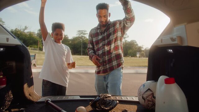 Man opening trunk and grabbing baseball bat and gloves