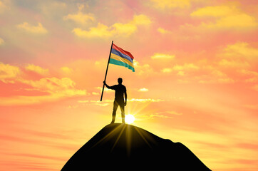 Waving flag of Mauritius at the top of a mountain summit against sunset or sunrise. Mauritius flag for Independence Day.