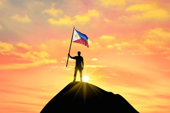 Waving flag of Philippines at the top of a mountain summit against sunset or sunrise. Philippines flag for Independence Day.