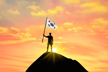 Waving flag of South Korea at the top of a mountain summit against sunset or sunrise. South Korea flag for Independence Day.