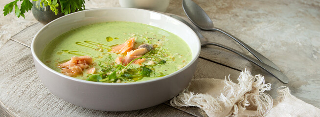 bowl of zucchini and broccoli soup with salmon on the table