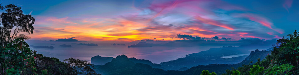 A panoramic view of the serene landscape at sunset, with mountains in the background and calm waters reflecting vibrant colors of orange, blue, green, yellow, pink, purple, and red
