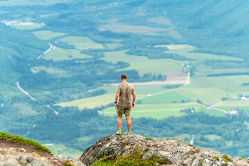 Obraz premium male backpacking hiker with yellow backpack climbing Romsdalseggen trail in Andalsnes Norway in summer with rocky mountains in the background