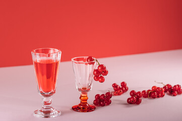 Glass glasses with red currants and red drink, creative still life with red berries on a red background. Selective focus.