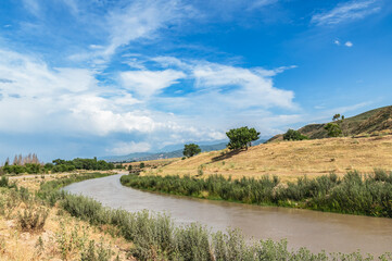 A river in a dry mountain valley and a blue sky with clouds.