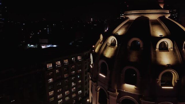 Two ancient illuminated domes and the Obelisk of Buenos Aires at night. Aerial camera approaches the domes and reveals the obelisk in the background