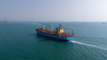 Fototapeta premium Aerial top view over international containers cargo ship at industrial import-export port prepare to load containers with big container loader ship vessel. global transportation and logistic business