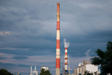 Obraz premium Industrial Chimneys Emitting Smoke Under Cloudy Sky In The City