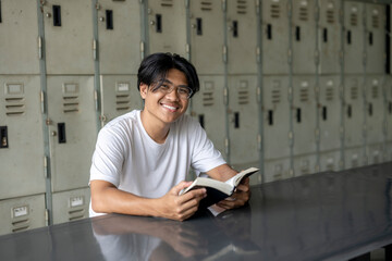Naklejka premium A young man is sitting at a table with a book in his hands