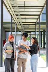 Obraz premium Three young people are walking down a hallway, each carrying a laptop