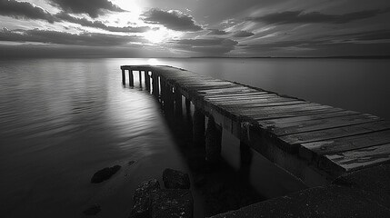 Monochrome old pier with colorful sunset reflections, end of day beauty