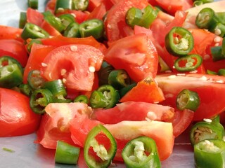 Sliced tomatoes with Chopped green chili pepper in a top.Cutted tomato piece with cutted green chillies pattern background 