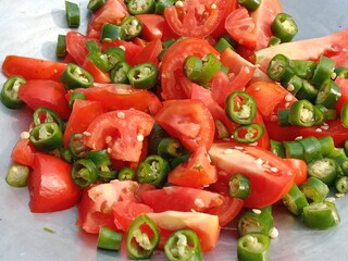 Sliced tomatoes with Chopped green chili pepper in a top.Cutted tomato piece with cutted green chillies pattern background 