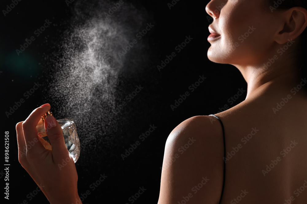 Canvas Prints Woman spraying perfume on black background, back view