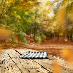 Old wooden board table with empty copy space for products. Autumn trees in a park background. Image for montage objects display.