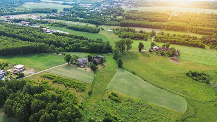 Aerial view of lush green forest and fields in summer evening countryside