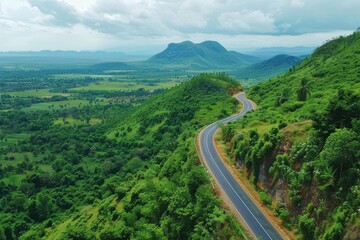 Fototapeta premium A bird's eye perspective of a paved pathway through lush woodlands, winding tar road amidst vibrant mountain forests, rural route traversing verdant woodlands and hills
